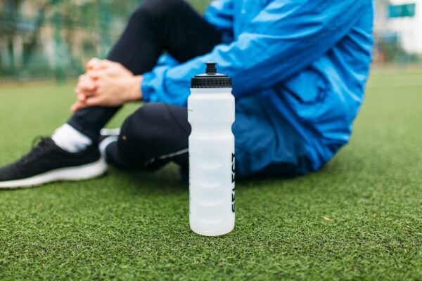 The guy is resting after a good workout. Guy after exercise, drinking water on the football field. Portrait of beautiful Guy in sportswear.